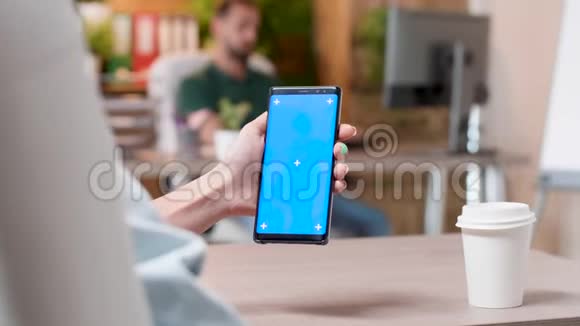 女人手里拿着一部智能手机上面有一个蓝色屏幕的独立模拟视频的预览图