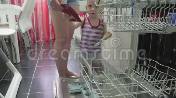 小男孩帮助母亲清空洗碗机休闲的生活方式在现实生活的内部视频的预览图