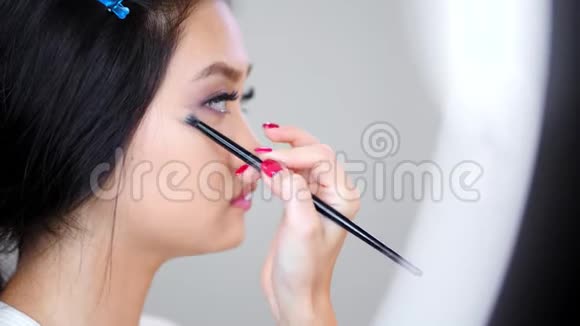 化妆师化妆时亚洲美女在画室照镜子视频的预览图