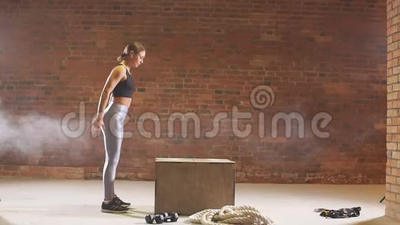 女孩在训练中跳进木箱交叉健身慢动作视频的预览图
