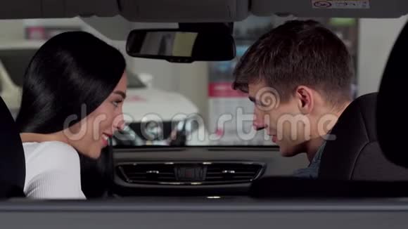 可爱的一对夫妇坐在经销商的新车里拿出相机的钥匙视频的预览图