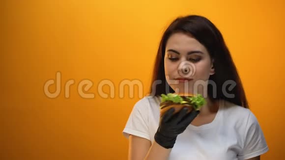女孩闻着汉堡对着镜头展示美味的快餐优质的产品视频的预览图