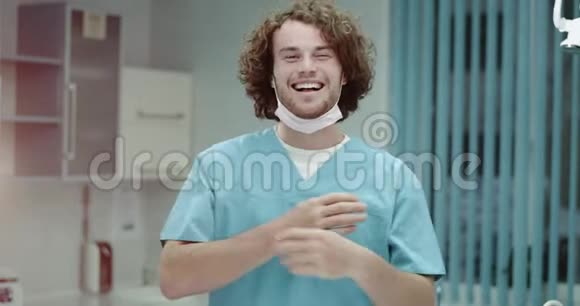 一位微笑的年轻医生或医生戴上手术面罩直视镜头的肖像视频的预览图