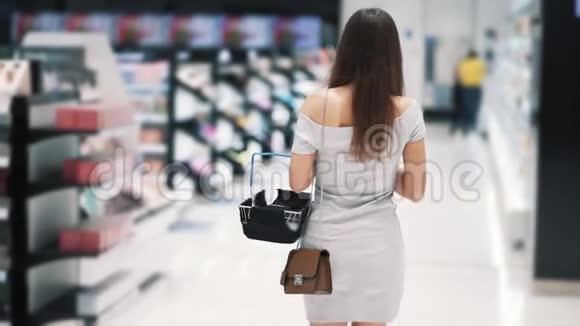 背面风景女孩在化妆品商店购物带篮子慢动作视频的预览图