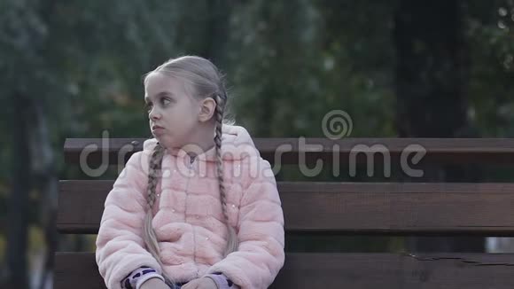 心烦意乱的小女孩坐在公园的长椅上感到孤独缺乏交流视频的预览图