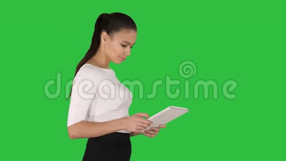 漂亮的女商人在绿色屏幕上行走时使用数字平板电脑Chroma键视频的预览图