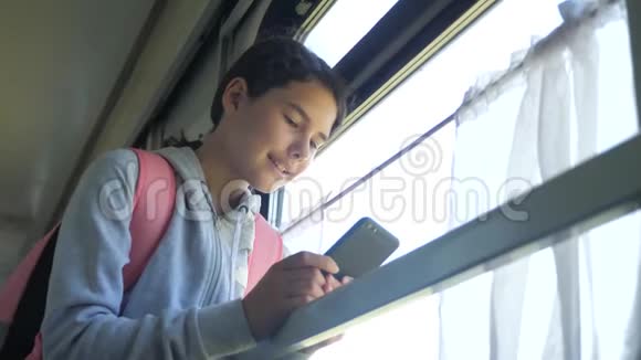 少女旅行者的生活方式与背包站在火车的窗口与智能手机旅费视频的预览图