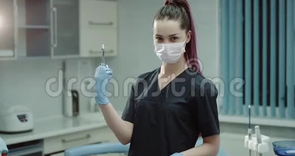 年轻的女牙医准备在镜头前拿着一个外科注射器进行注射并戴着一个外科医生视频的预览图