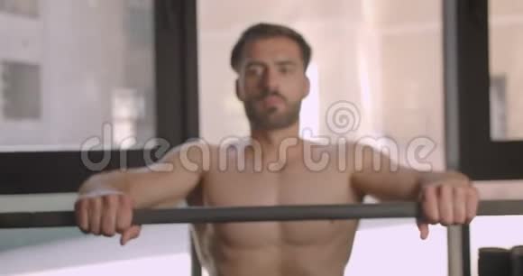 赤膊肌肉发达的白种人男子举重努力站在健身房室内的特写照片视频的预览图