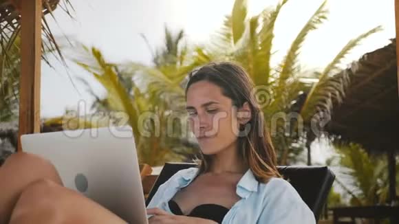美丽的白种人工作狂首席执行官女商人工作打字在笔记本电脑移动办公室在海滩椅子度假视频的预览图