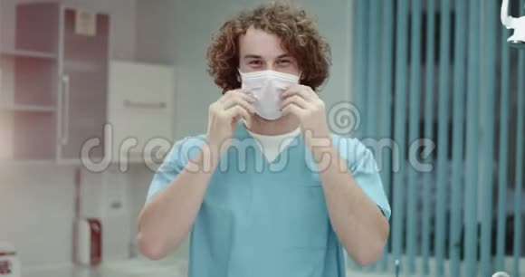 在医院里非常有魅力的年轻医生或外科医生摘下手术面罩在前面微笑着视频的预览图