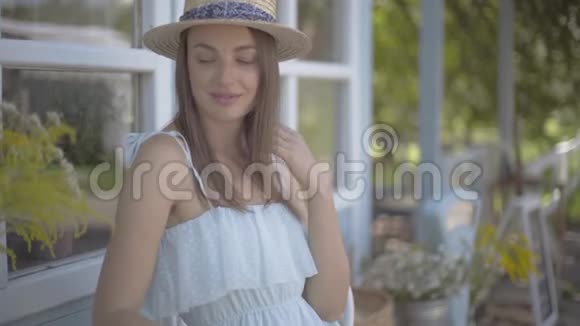 美丽的年轻女子戴着草帽看着相机在户外快乐地微笑着情感乡村生活方式自然视频的预览图