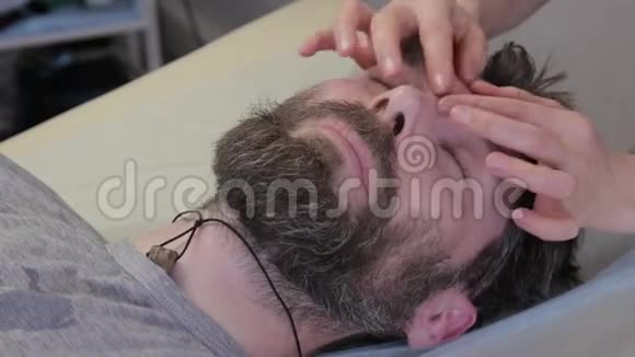 去做面部按摩美容程序预防皮肤老化躺在科斯莫医生的办公室里视频的预览图