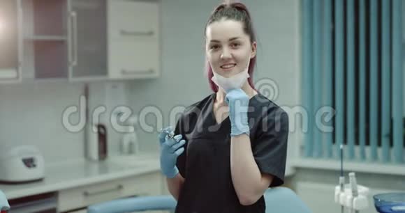 一位年轻的牙医或牙医助手的肖像直视着相机拿着一个外科注射器视频的预览图