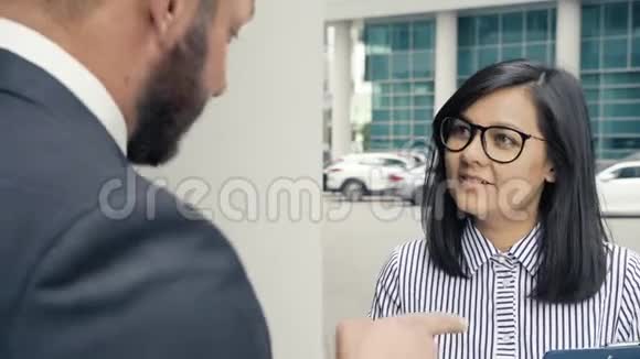 商务男士在办公楼入口处迎接一位年轻女士视频的预览图