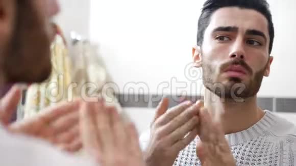 英俊的年轻人在脸上涂抹保湿霜视频的预览图