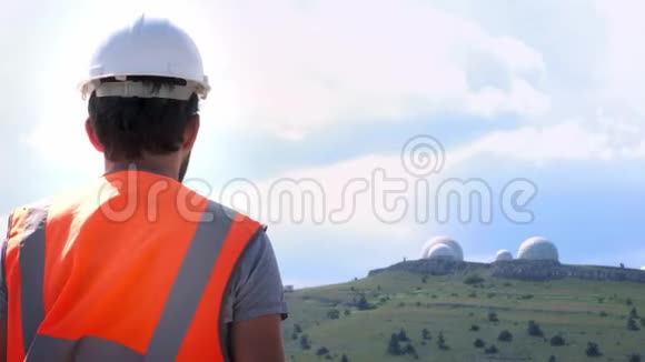 一位身穿白色头盔和背心的男工程师或建筑工人拍摄了山顶天文台的照片视频的预览图