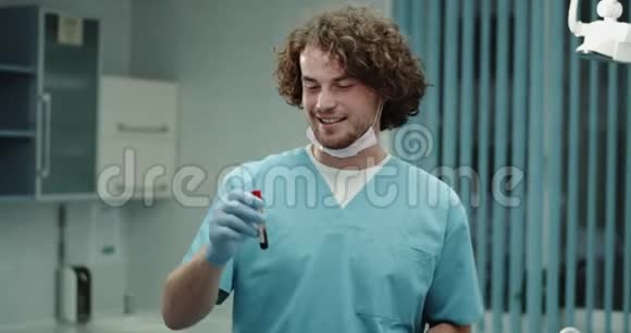 在现代充满魅力的医生男子肖像直视镜头手里拿着病人的血盆大口视频的预览图