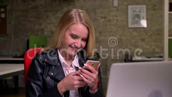 漂亮的金发白种女人坐着拿着手机脸上洋溢着幸福和灿烂的笑容视频的预览图