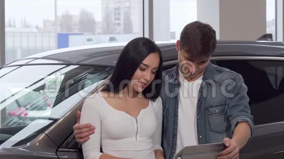 快乐的情侣拥抱在经销商沙龙拿着车钥匙视频的预览图