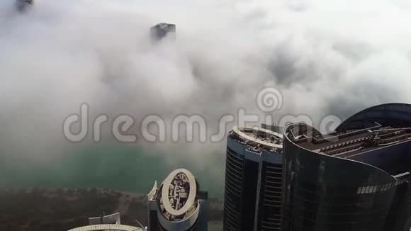 从空中俯瞰城市中一个湖泊周围的摩天大楼周围是雾云视频的预览图