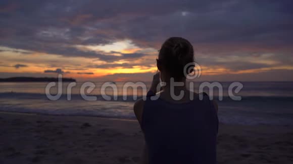一位年轻女子在海滩上观看一场美妙的日落时慢镜头视频的预览图