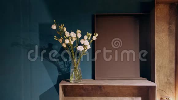 玻璃花瓶与轻轻的粉红色康乃馨站在一张木桌上的背景墙内部的一部分视频的预览图
