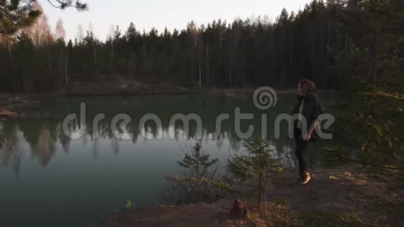年轻女子在拉脱维亚波罗的海国家的一个绿松石色湖上用手机拍照视频的预览图