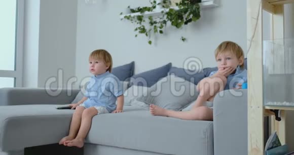 孩子们正在看电视坐在沙发上看动画片的小孩子视频的预览图