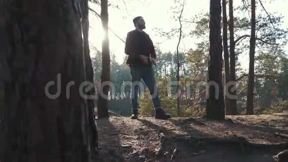 小胡子拿着斧头在森林里散步砍了一棵树在户外用斧子清除森林视频的预览图
