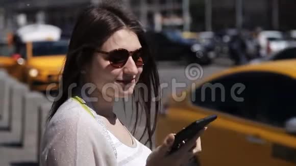 一个女孩在一个阳光明媚的日子里一条经过的小溪的背景下在街上使用手机女孩用的是视频的预览图