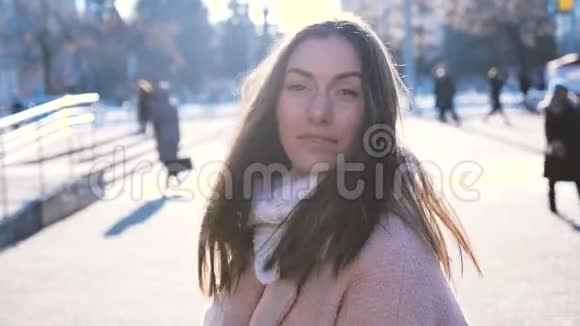 城市街道上身着时髦外套和围巾的满意黑发女人的肖像慢镜头微笑视频的预览图