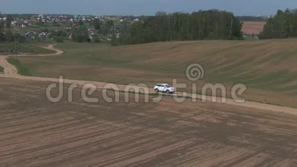 空中镜头白色汽车在田野上行驶视频的预览图