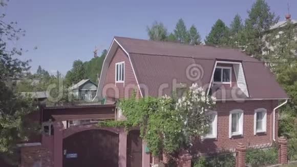 可爱的红砖房子盛开的灌木丛和绿树围绕着它生长库存录像地政及景观视频的预览图