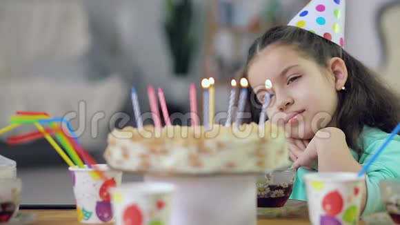 一个小女孩看着有蜡烛的蛋糕很伤心视频的预览图