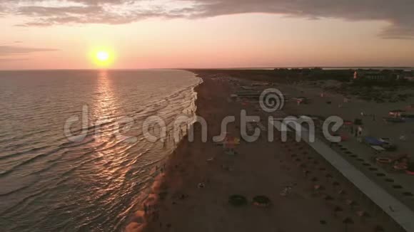 鸟瞰美丽的日落越过大海和沙滩人们在海浪中游泳视频的预览图