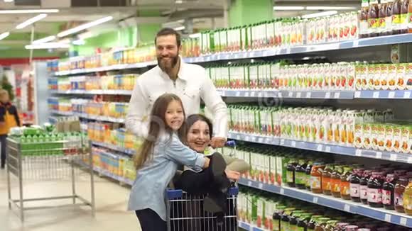 幸福的家庭在超市里玩得开心妈妈坐在购物车里视频的预览图