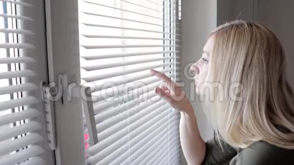 好奇的年轻女人在家里偷窥百叶窗视频的预览图