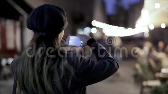 高清镜头显示年轻漂亮时髦的黑发女人晚上站在街上拍照或录像视频的预览图