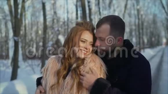 女孩和男孩在公园里晒冬天那个家伙和那个女孩正在冬天的森林里休息年轻夫妇走路视频的预览图