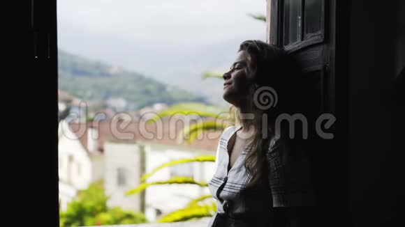 村里山间别墅阳台上微笑的女士视频的预览图