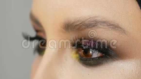 专业化妆师在模特眼上用不同颜色着色的假黑色长睫毛视频的预览图