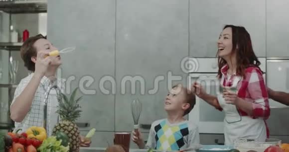 成熟的父母和他们的两个儿子在现代厨房里玩泡泡视频的预览图