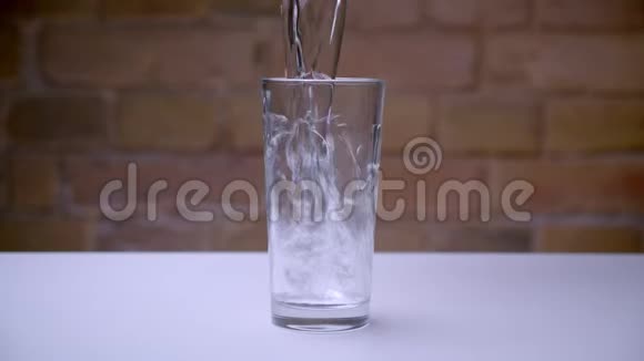 透明玻璃的特写镜头站在白色的桌子上水被倒进桌子里视频的预览图