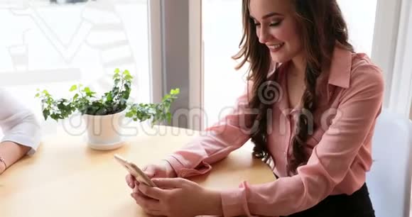 女孩坐在时髦的咖啡店里带着智能手机视频的预览图