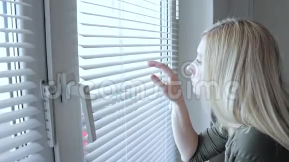 好奇的年轻女人在家里偷窥百叶窗视频的预览图