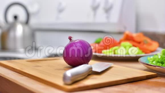 女人用菜刀在木板上切鲜红洋葱视频的预览图