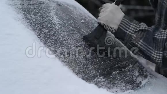 人用刷子擦车上的雪冬季暴风雪在降雪期间人从汽车挡风玻璃上移除雪冬天下雪了视频的预览图