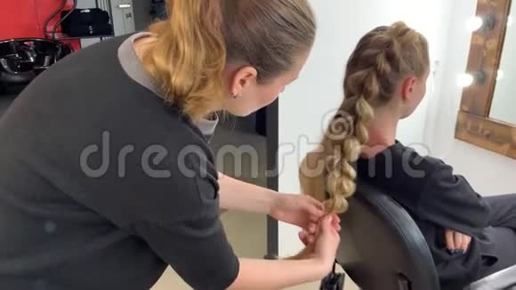 理发师编辫子的女人在美发沙龙头发视频的预览图