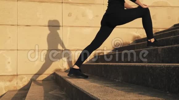 穿着黑色运动服的女人在训练中弯曲大腿内侧的肌肉女孩伸展腿部肌肉之前视频的预览图